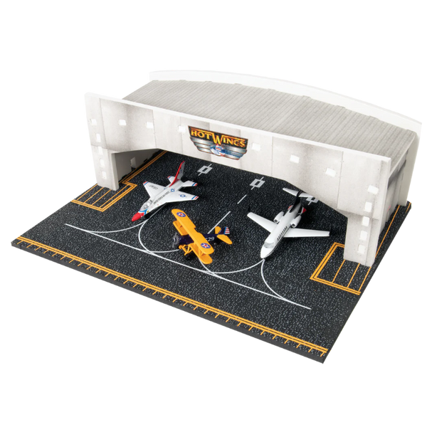 Model airplane set on a HotWings branded play mat with a small building structure.